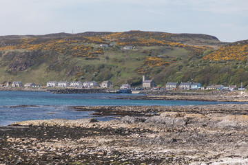 The rocky foreshore of Rathlin Island curving around to the main settlement and port.
