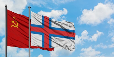 Soviet Union and Faroe Islands flag waving in the wind against white cloudy blue sky together....