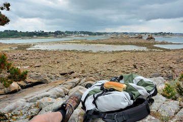 Casse-croûte et sac à dos d'un randonneur posés sur un rocher au bord de la mer
