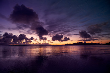 Dark and moody sunset reflecting on the calm waters of the Indian Ocean on the island of Mahe in the Seychelles
