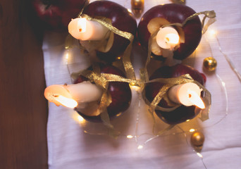 Four candles in four apples - a beautiful decoration for the Christmas table. Concept for christmas eve. Soft focus of cadles  