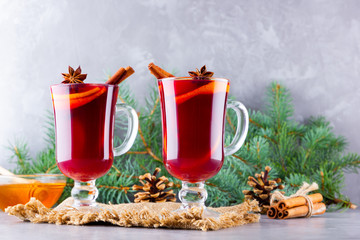 Mulled wine and fir branches on burlap. Mulled wine with oranges, honey, cinnamon and cloves on cement background. Hot wine with honey and spices