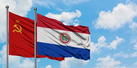 Soviet Union and Paraguay flag waving in the wind against white cloudy blue sky together. Diplomacy...