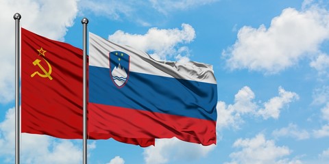 Soviet Union and Slovenia flag waving in the wind against white cloudy blue sky together. Diplomacy concept, international relations.