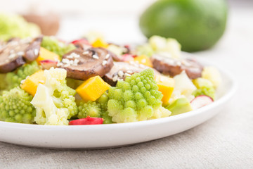 Vegetarian salad from romanesco cabbage, champignons, cranberry, avocado and pumpkin on a white wooden background. side view, selective focus