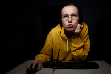 girl gamer playing a video game on a computer at night at home, a student focused on the game