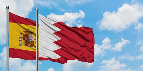 Spain and Bahrain flag waving in the wind against white cloudy blue sky together. Diplomacy concept, international relations.