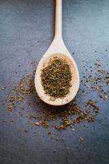 Fresh dry oregano and basil on wooden spoon with concrete background. Seasoning products. Close up view. Vertical picture.
