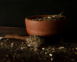 cazuela de barro con yerba mate derramada sobre superficie de madera