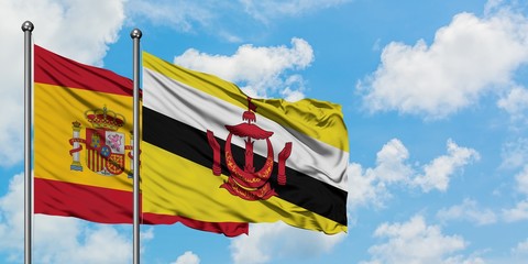 Spain and Brunei flag waving in the wind against white cloudy blue sky together. Diplomacy concept, international relations.