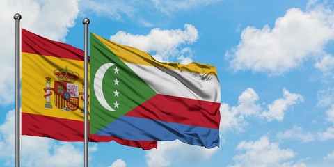 Spain and Comoros flag waving in the wind against white cloudy blue sky together. Diplomacy concept, international relations.