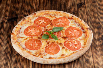 Classic italian Margherita with melted cheese and tomatoes on wooden rustic table