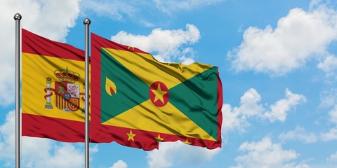Spain and Grenada flag waving in the wind against white cloudy blue sky together. Diplomacy concept, international relations.