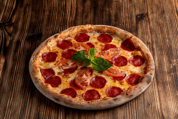 Hot pepperoni pizza with spicy sausage and melted cheese on wooden table