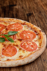 Close up of classic italian Margherita with melted cheese and tomatoes on wooden rustic table