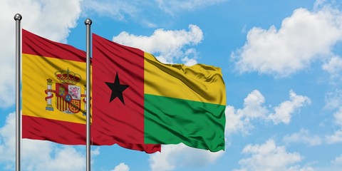 Spain and Guinea Bissau flag waving in the wind against white cloudy blue sky together. Diplomacy concept, international relations.
