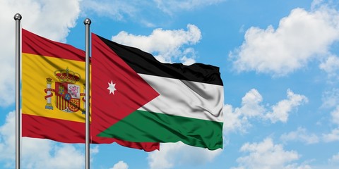 Spain and Jordan flag waving in the wind against white cloudy blue sky together. Diplomacy concept, international relations.