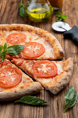 Close up of classic italian Margherita with melted cheese and tomatoes on wooden rustic table