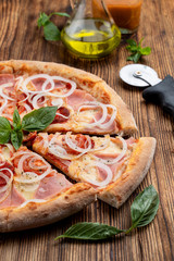 Close up of italian pizza with pork ham, red onions and hot melted cheese