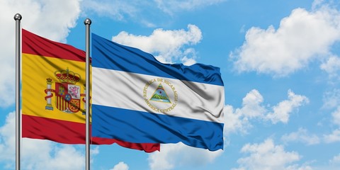 Spain and Nicaragua flag waving in the wind against white cloudy blue sky together. Diplomacy...
