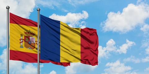 Spain and Romania flag waving in the wind against white cloudy blue sky together. Diplomacy...