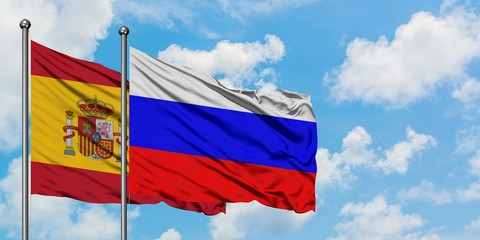 Spain and Russia flag waving in the wind against white cloudy blue sky together. Diplomacy concept,...
