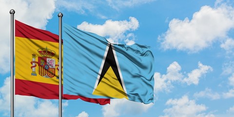 Spain and Saint Lucia flag waving in the wind against white cloudy blue sky together. Diplomacy concept, international relations.