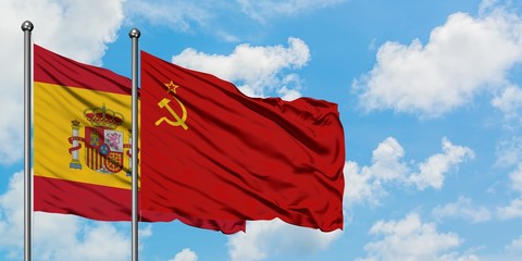 Spain and Soviet Union flag waving in the wind against white cloudy blue sky together. Diplomacy concept, international relations.