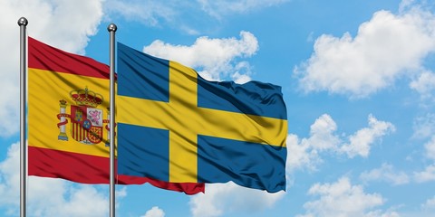 Spain and Sweden flag waving in the wind against white cloudy blue sky together. Diplomacy concept, international relations.