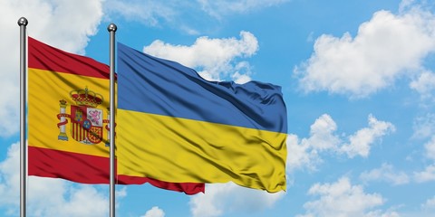 Spain and Ukraine flag waving in the wind against white cloudy blue sky together. Diplomacy concept, international relations.