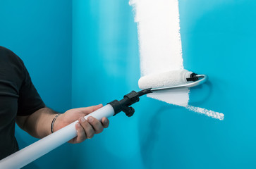 Young man painting wall with paint roller. Man at work concept