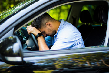 Portrait of tired businessman driving a car