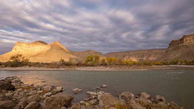 Time lapse of sunlight shining through the clouds on desert landscape of Grays Canyon as the Green River flows past Swasey's Beach.