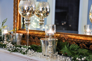 A traditional fireplace mantle is beautifully decorated for Christmas with mercury glass candle...