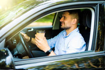 Naklejka premium Young man drinking coffee while driving the car