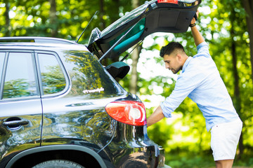 Young handsome man on a road trip, opening his trunk. © F8  \ Suport Ukraine