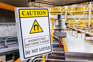 Magnetic field hazard symbol posted in a laboratory; Warning posted: 'Caution; Magnetic field may exceed 5 Gauss; Do not loiter