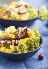 Vegetarian salad from romanesco cabbage, champignons, cranberry, avocado and pumpkin on a black concrete background. side view, selective focus.