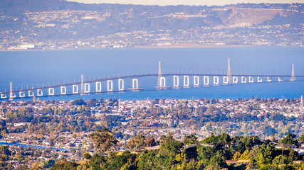 Aerial view of San Mateo Bridge, connecting the Peninsula and East Bay; residential areas of Foster City visible in the foreground ; San Francisco Bay Area, California