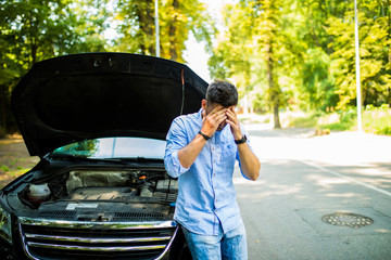 Young man on the road having problem with a car. Broken down car on the road. Traveling problem in...