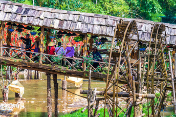 Cat Cat, Vietnam - 10th October 2019: Tourists sit on the bridge over the river in Cat Cat Village, near Sapa in Northern Vietnam. A famous holiday destination