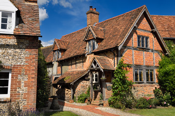 Red brick and roof tile English Tudor cottages in Turville in full sun with blue sky Buckinghamshire England