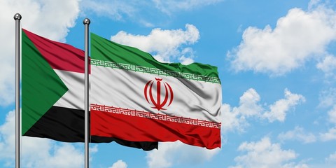 Sudan and Iran flag waving in the wind against white cloudy blue sky together. Diplomacy concept, international relations.