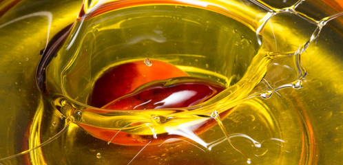 Red Palm seed dropped in cooking palm oil with a splash in glass. Organic palm oil can be processed for food industry and produce energy as biodiesel and important agriculture economy in tropical Asia - obrazy, fototapety, plakaty