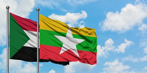 Sudan and Myanmar flag waving in the wind against white cloudy blue sky together. Diplomacy...