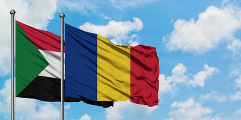 Sudan and Romania flag waving in the wind against white cloudy blue sky together. Diplomacy...