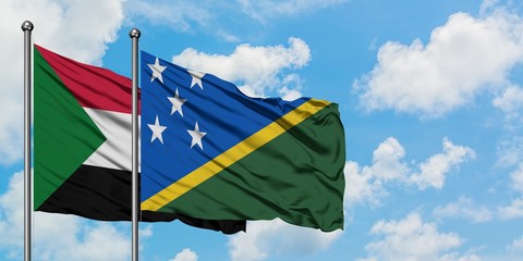 Sudan and Solomon Islands flag waving in the wind against white cloudy blue sky together. Diplomacy concept, international relations.