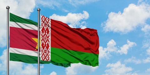 Suriname and Belarus flag waving in the wind against white cloudy blue sky together. Diplomacy...