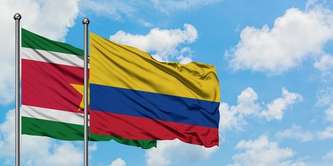 Suriname and Colombia flag waving in the wind against white cloudy blue sky together. Diplomacy concept, international relations.