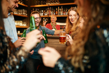 Group of friends drinking beer, chatting and having good time at pub. Night out.